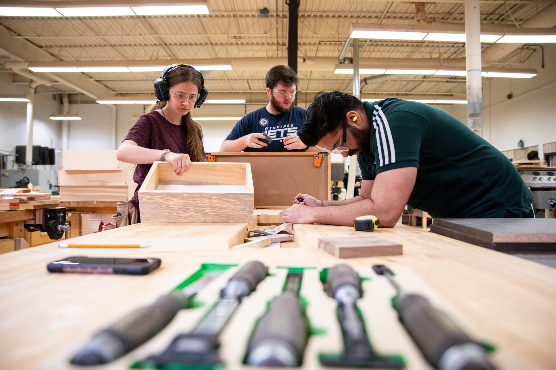 三名学生在橱柜和木工项目中合作