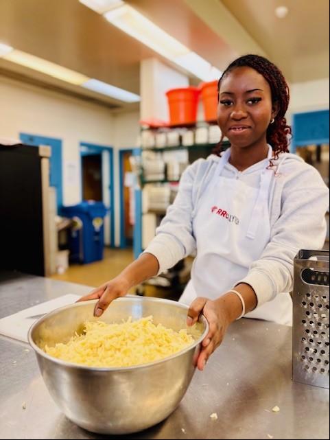 一名学生拿着一碗土豆对着镜头微笑。