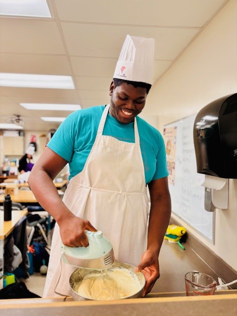 一名学生用手动搅拌机混合配料。