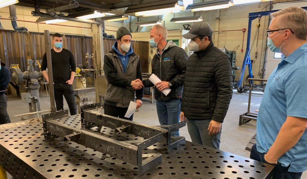 e8体育 焊接专业学生与 West End Radiators 工作人员握手