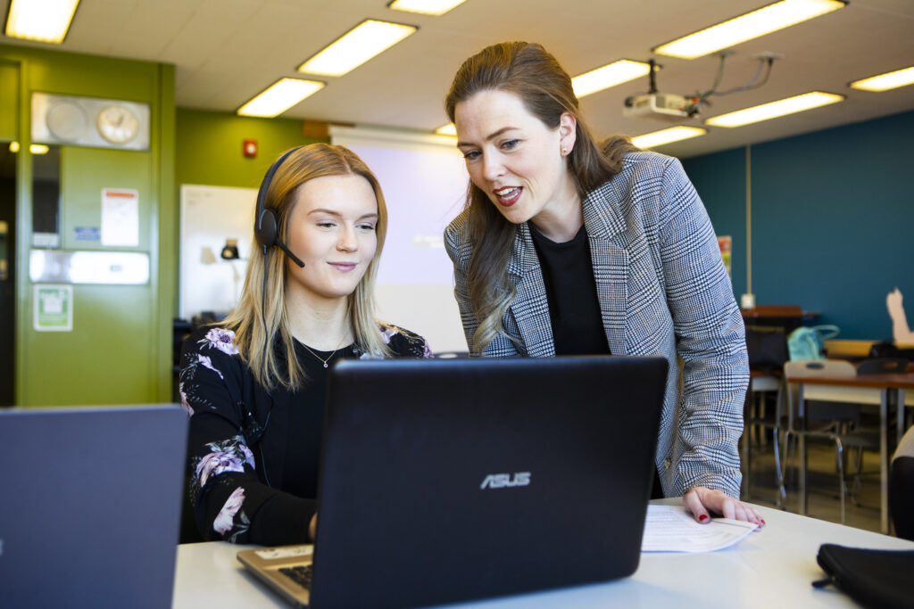 行政助理学生和讲师，在笔记本电脑前交谈