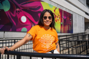 RRC E8体育比分莱蒂西亚·斯宾塞 (Leticia Spence)，戴着墨镜，站在圣母院校园的土著壁画前。