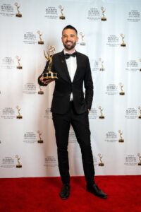 ABC News reporter Austin Grabish holding an Emmy awards on the red carpet.