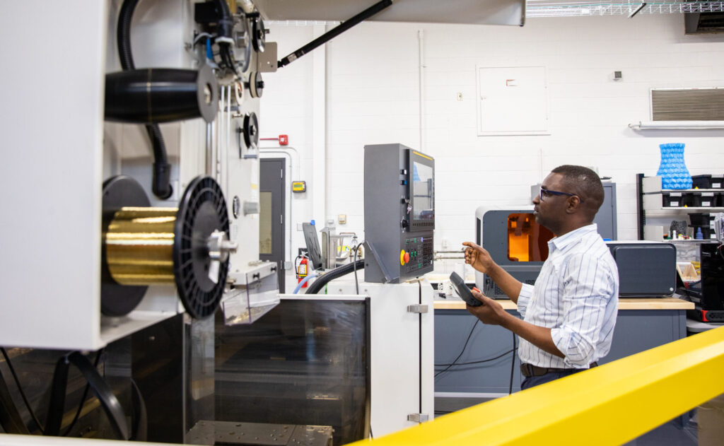 男性研究员在 e8体育 航空航天与制造技术访问中心 (TACAM) 的设备上工作。