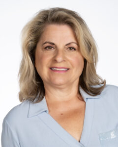 Smiling woman with mid-length blonde hair, wearing light blue blouse.