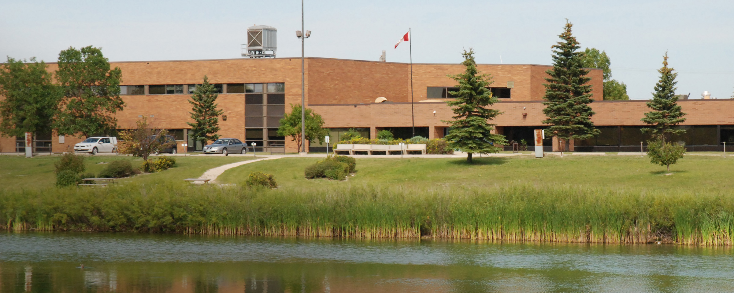 一栋棕色建筑的外部，前景是一个池塘