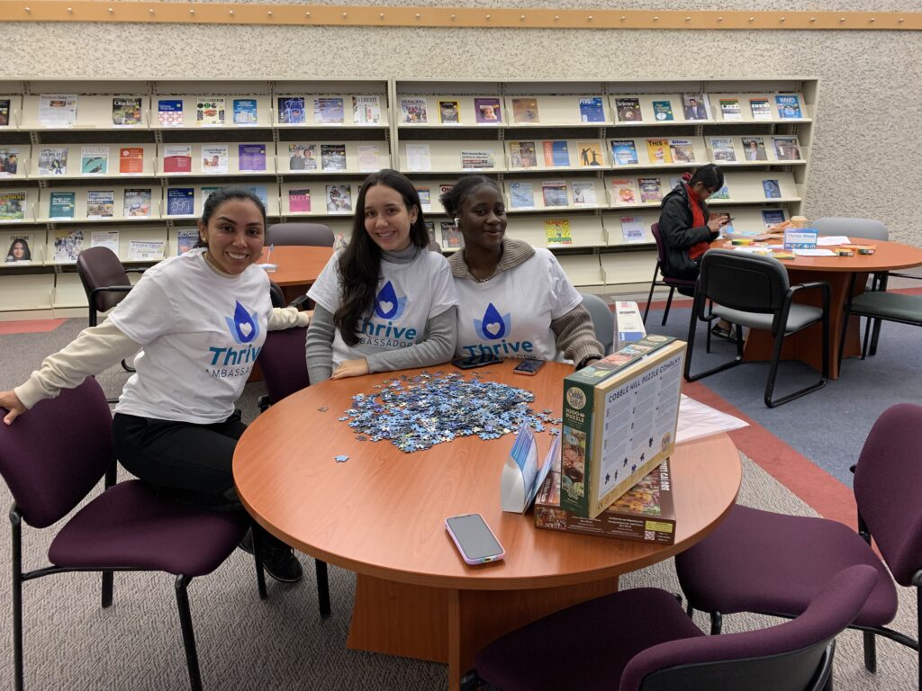 三位蓬勃发展大使在图书馆的拼图桌旁工作。