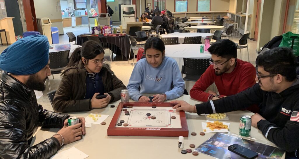 一群学生在桌边玩卡罗姆游戏。