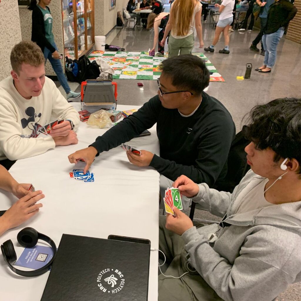 一群学生围着桌子玩乌诺游戏。