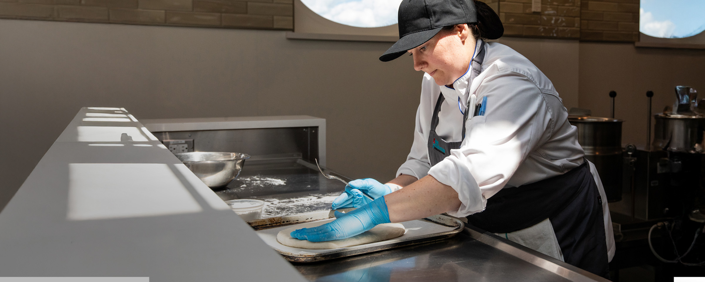 女性土著烹饪学生在烤盘上塑造面团。